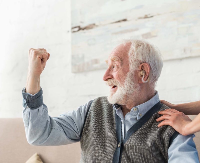 Heureux homme âgé avec prothèse auditive regardant ailleurs